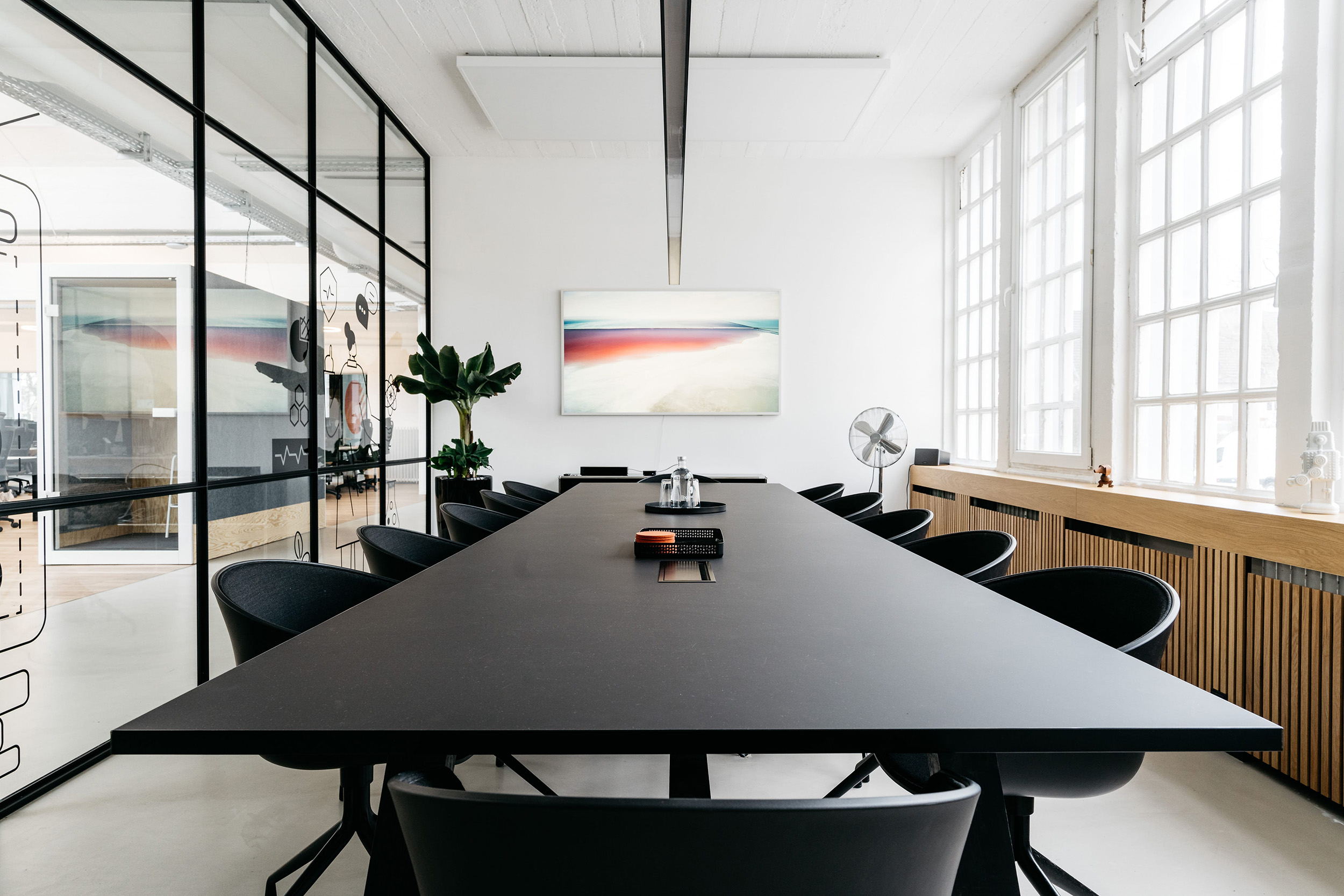 Heller Besprechungsraum bei pace-IT Köln mit großem Konferenztisch, Glaswänden und kreativer Wandgestaltung